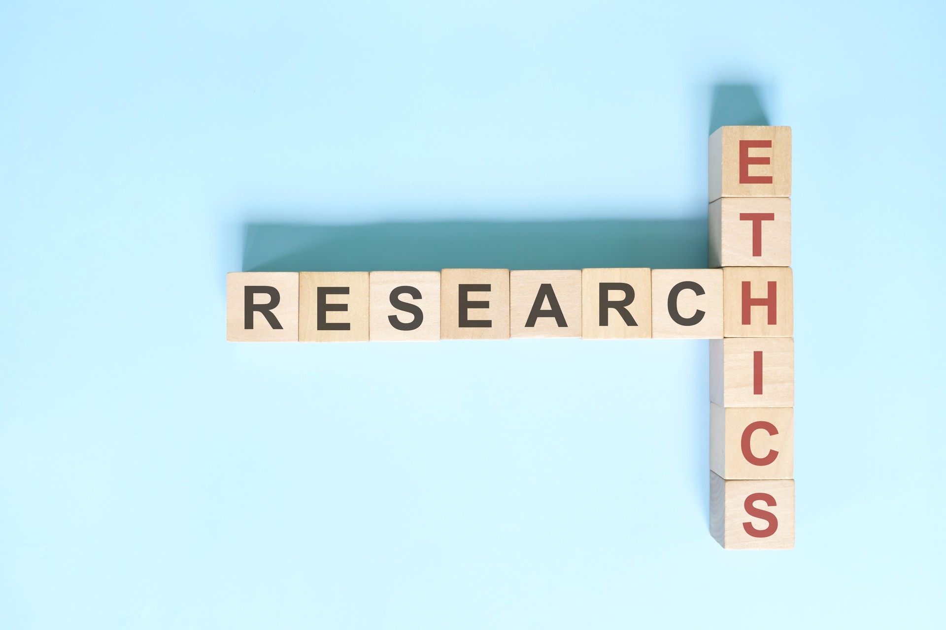 Research ethics concept. Crossword puzzle flat lay typography in blue background